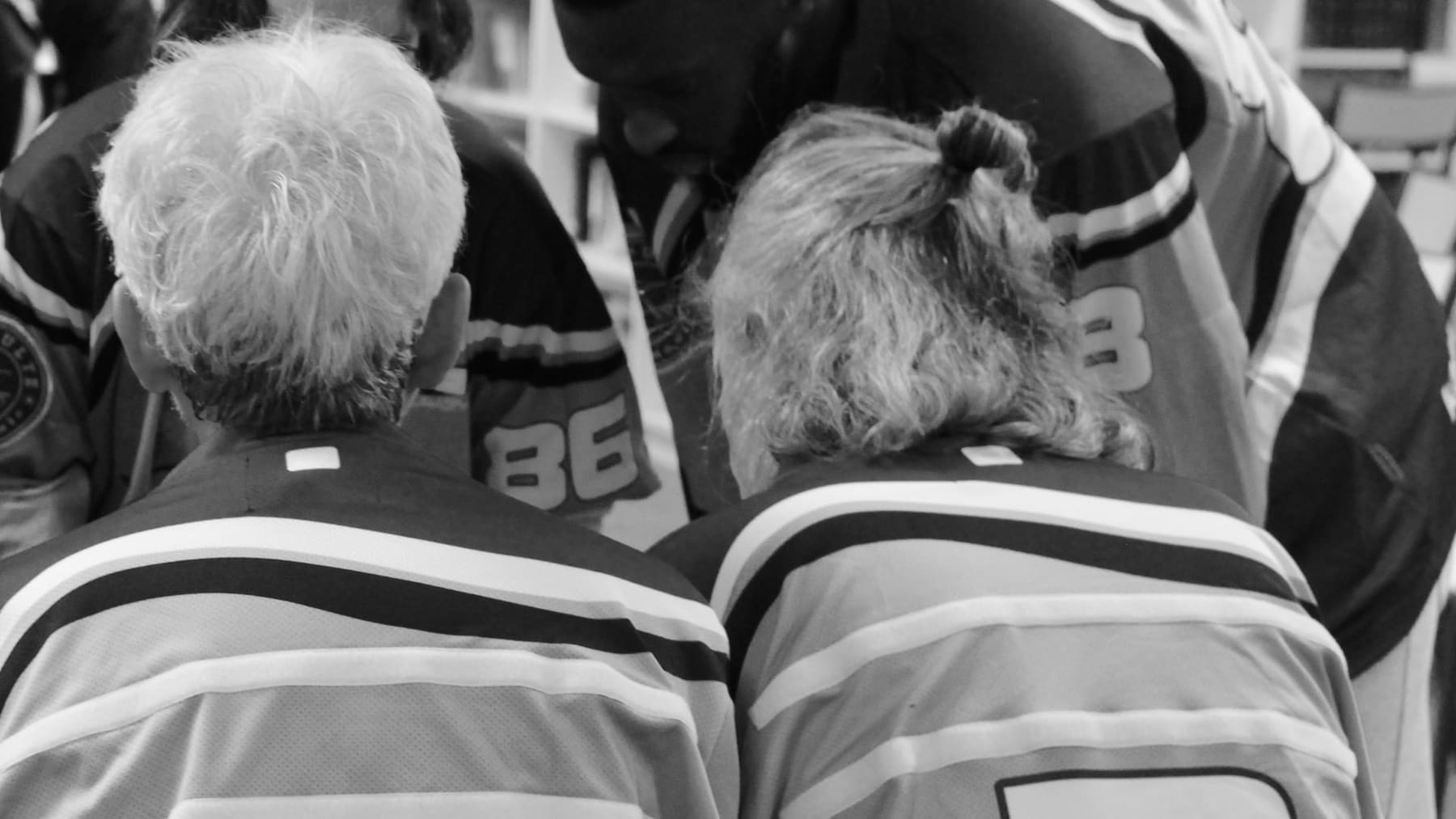 Deux joueurs de la Katapulte vus de dos, en maillot de match, penchés vers leur équipe pendant un caucus d'improvisation